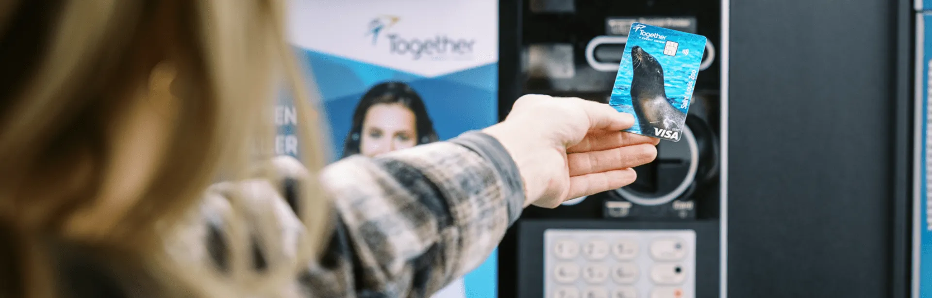 A person using a tap to pay method with their debit card at an atm.